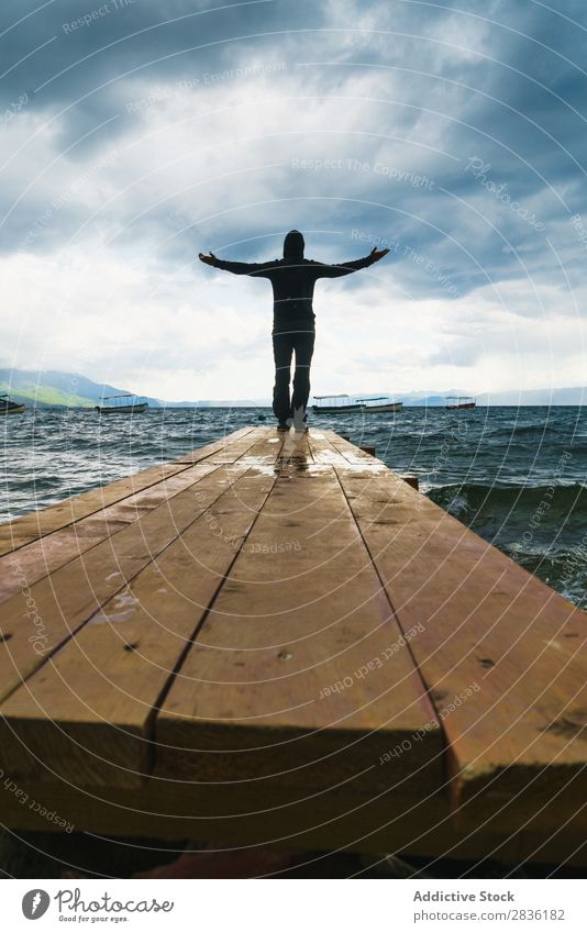 Anonymous man enjoying storm on pier Man Storm Ocean Freedom Dramatic fearlessness Nature Spirituality enjoyment Happiness Landscape Coast Stand traveler