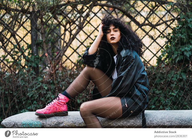 Woman on fence in park Attractive City fashionable Curly Fence holding hair Park Brunette Jacket Fashion Youth (Young adults) Beautiful pretty Street Model