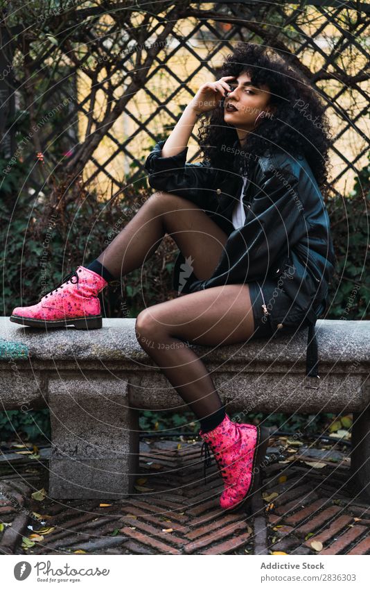 Woman on fence in park Attractive City fashionable Curly Fence holding hair Park Brunette Jacket Fashion Youth (Young adults) Beautiful pretty Street Model