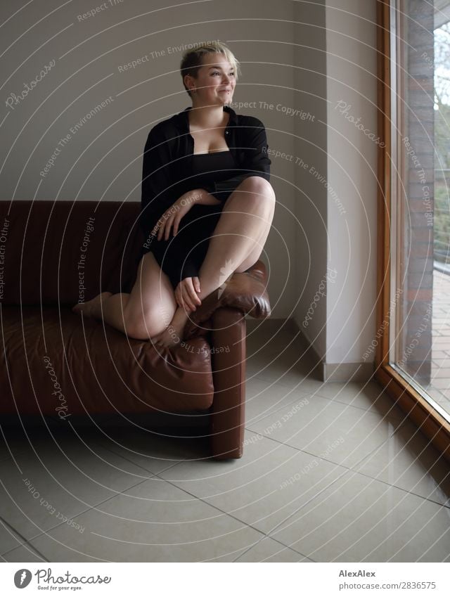 Young woman with long legs sits barefoot on the couch pretty Well-being Flat (apartment) Room Window Youth (Young adults) Legs 18 - 30 years Adults Barefoot