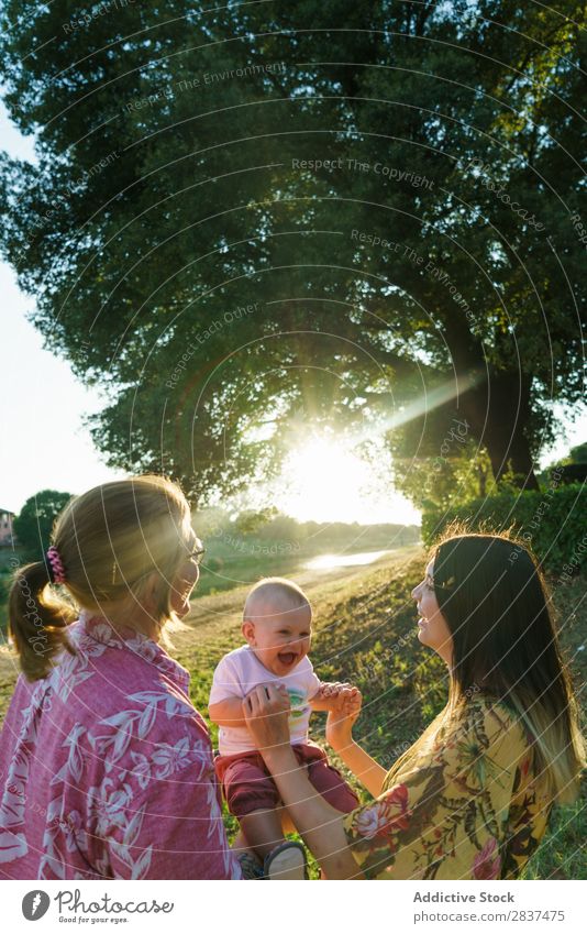 Happy lesbian couple with child Mother Child Park Green Sunbeam Human being Woman Happiness Summer Lifestyle Love same gender parents Homosexual Couple