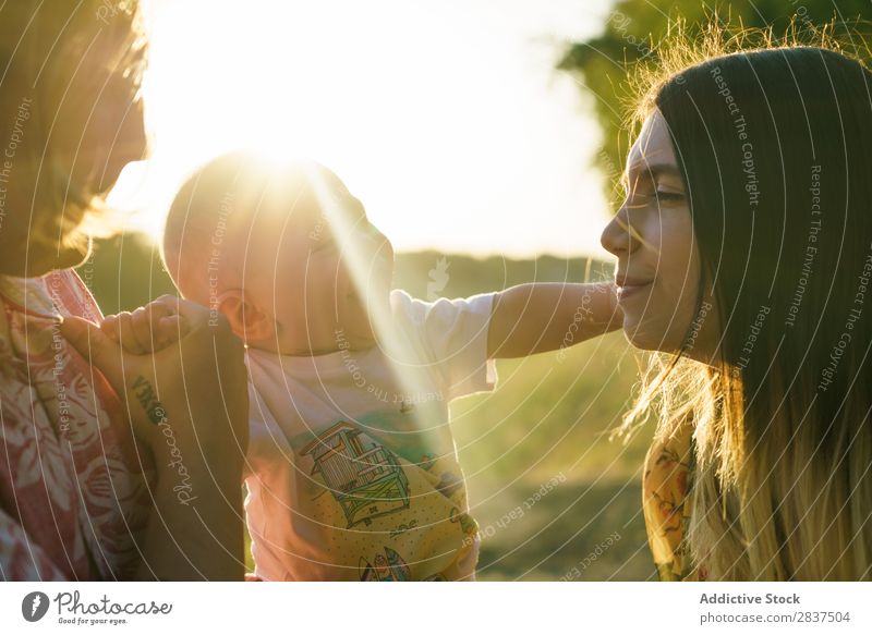 Happy family with child Mother Child Park Green Carrying Sunbeam Human being Woman Happiness Summer Lifestyle Love same gender parents Homosexual Couple