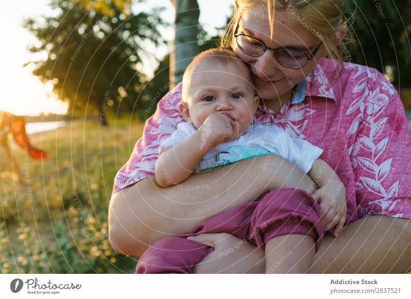 Mother sitting with kid on hands Child Park Lawn Green Sunbeam Family & Relations Happy Human being Woman Happiness Summer Lifestyle Love Parents Nature