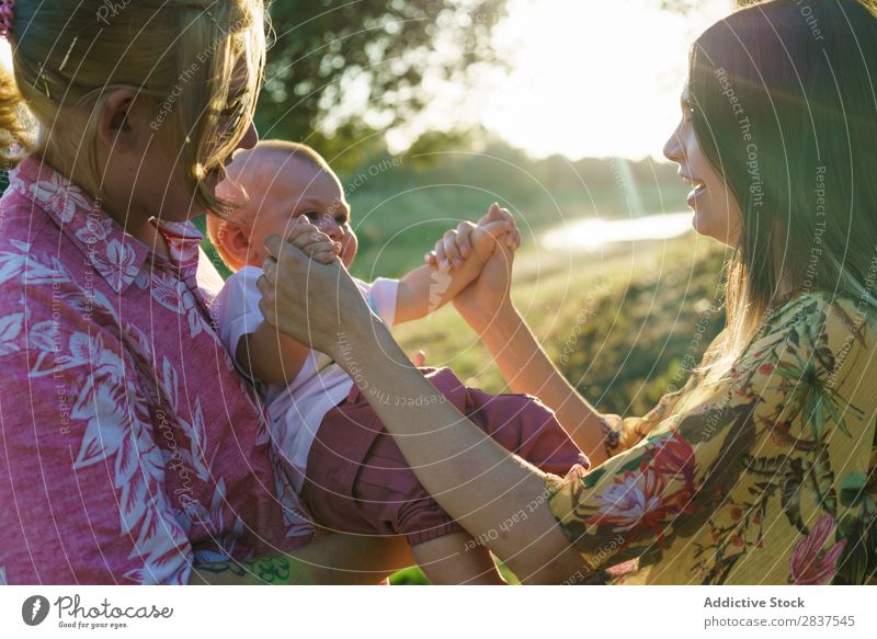 Happy lesbian couple with child Mother Child Park Green Sunbeam Human being Woman Happiness Summer Lifestyle Love same gender parents Homosexual Couple