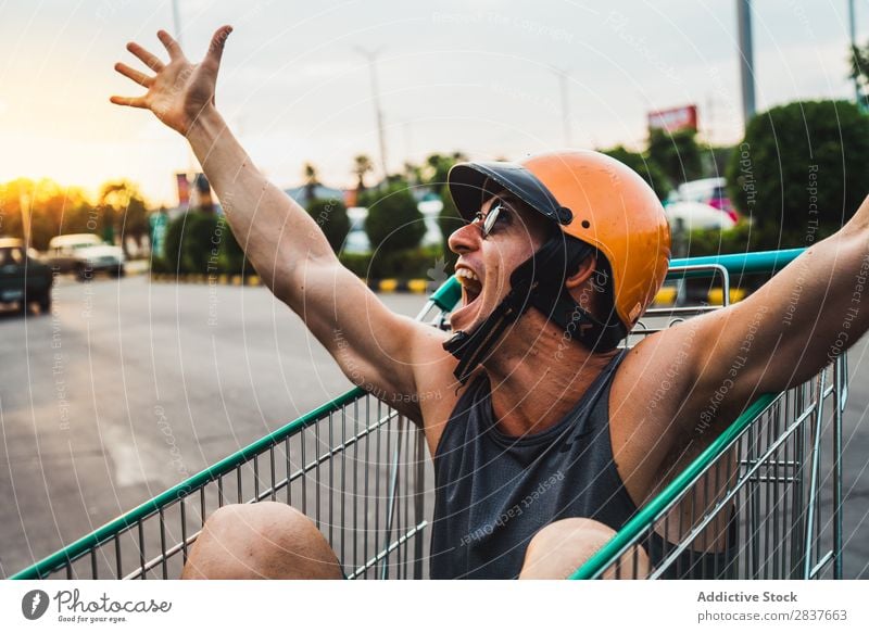 Emotional man in shopping cart Man Shopping Trolley riding Cart pushcart Sunglasses shopper Ride handsome Cheerful Joy Parking lot Human being Markets Humor