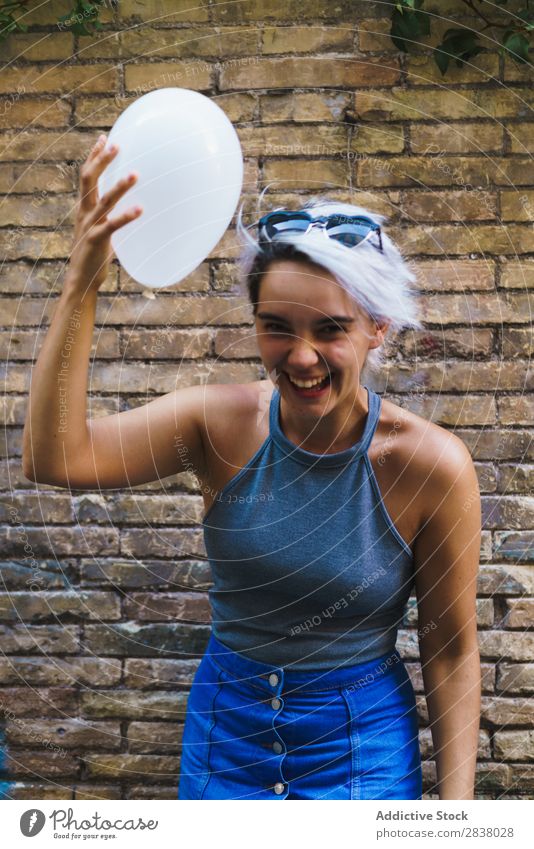 Charming woman posing with balloon Woman Posture Balloon Street Easygoing Summer Emotions Happiness Feminine Brick wall Contentment Expression City Model