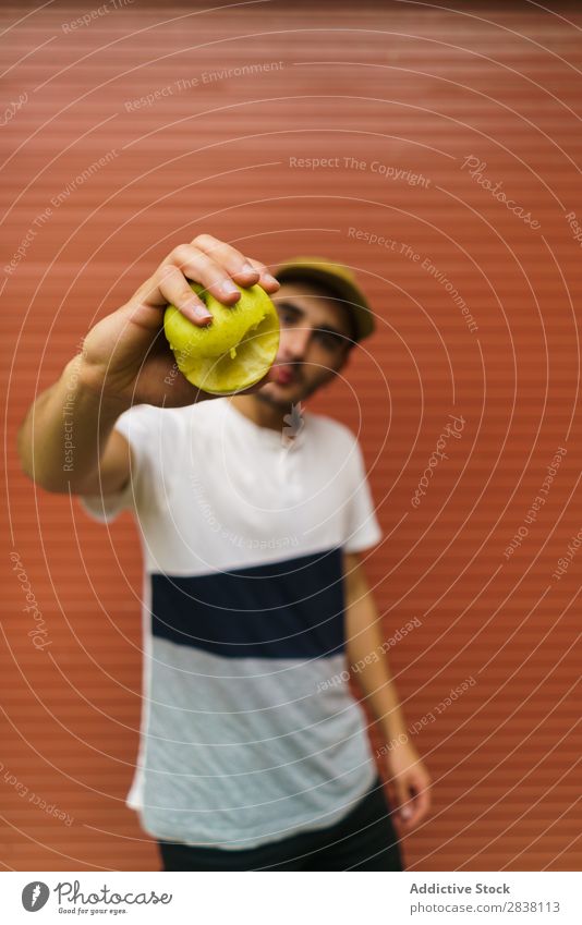 Man showing apple near wall Eating Appetite Expressive Posture facial Intellect Playful Youth (Young adults) Recklessness Vacation & Travel Lunch Summer Food