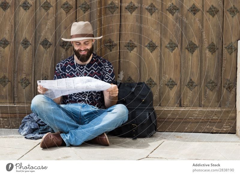 A tourist sitting and reading a map while listening to music Man Headphones Map Backpack Reading Lanes & trails searching Sit Vacation & Travel Tourism Ground