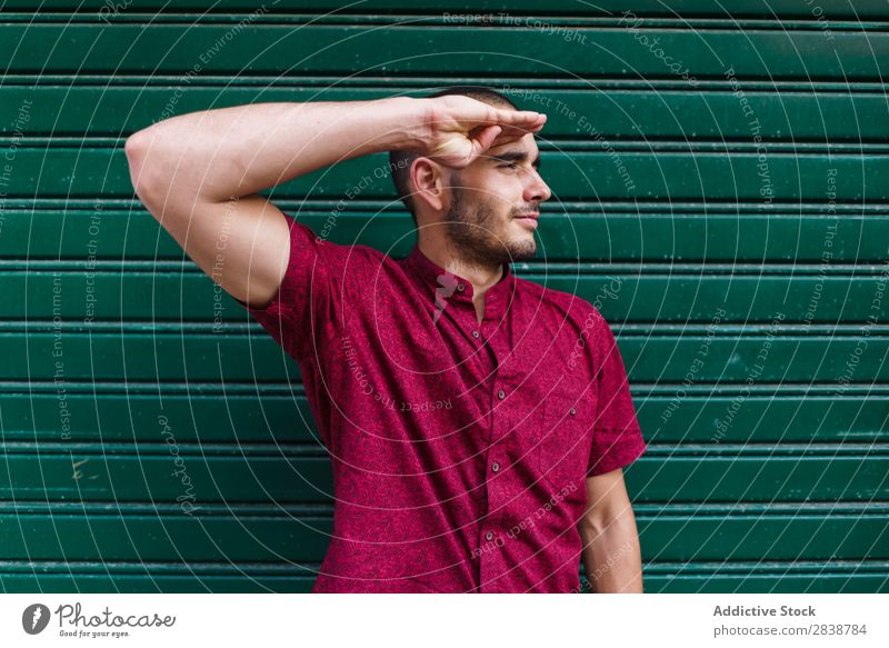 Casual man posing in green wall Man Indicate Musculature Expression pretending Self-confident Posture Town Playful human face Easygoing Biceps Exterior Street