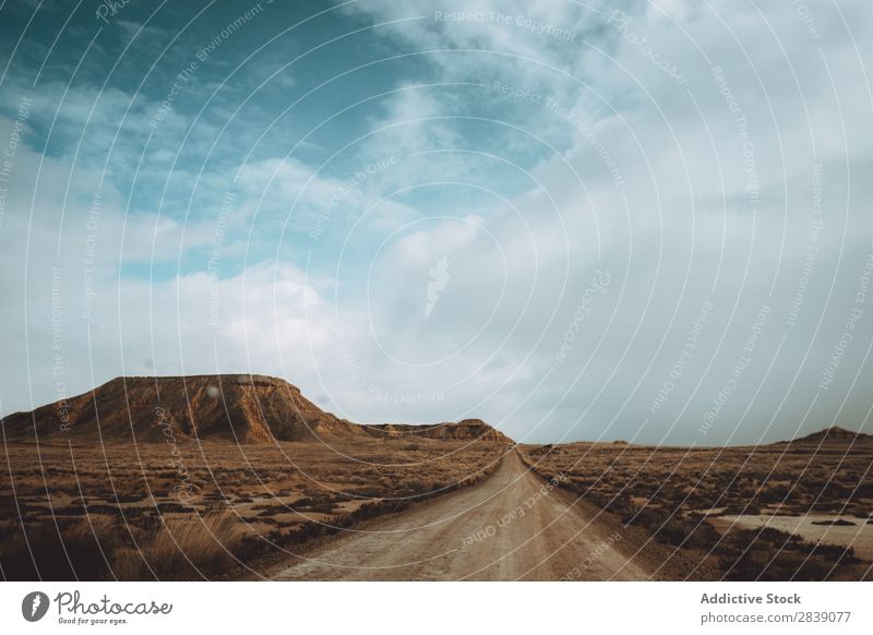 Dry road in cloudy day Street Nature Landscape Perspective Vacation & Travel Desert Landing Grass Sand Ground Environment Yellow Stone Wilderness Beautiful