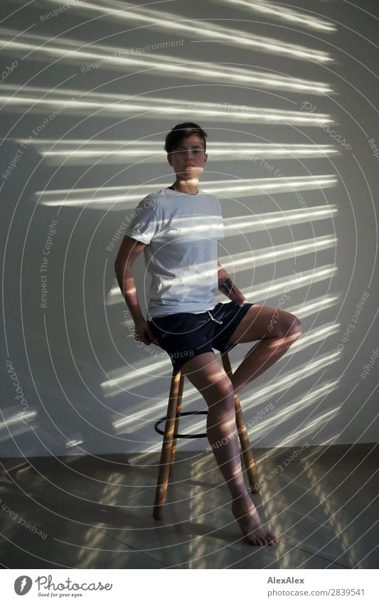 Young woman sitting on a stool illuminated in stripes of light Style Beautiful Life Room Stool Strip of light Light and shadow Youth (Young adults)