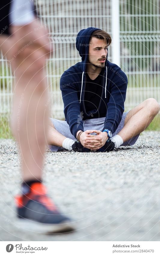 Two young men stretching after running in the street. Action Adults Athlete Attractive being Body Considerate Caucasian Practice Athletic Fitness flexibility