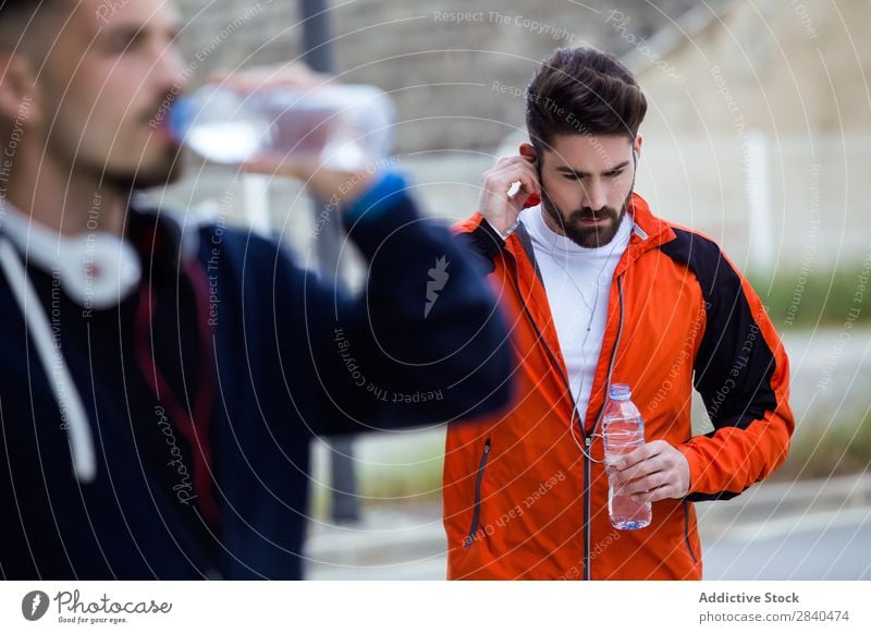 Two young men resting after running in the street. Action Adults Athlete Attractive being Body Considerate Caucasian Practice Athletic Fitness flexibility