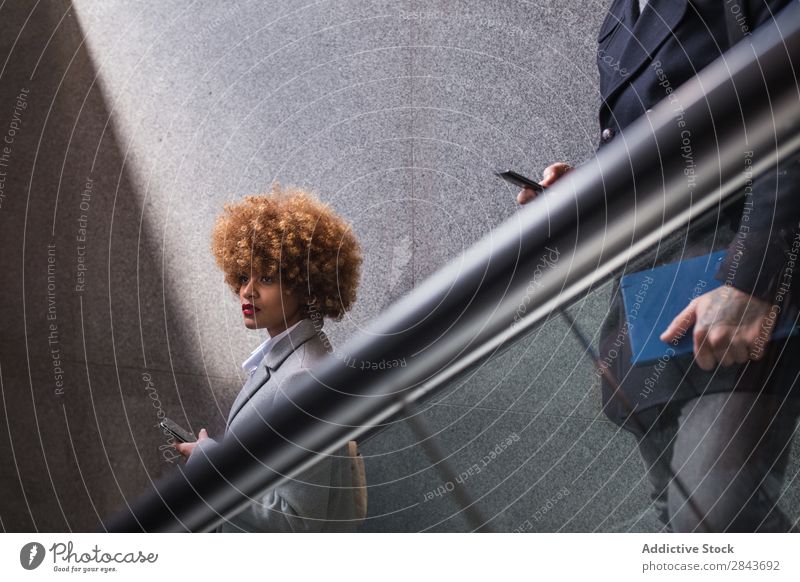 Stylish couple with phone on escalator Couple Adults Style Beautiful Escalator moving stairs PDA using Coat warm clothes Together handsome pretty Happiness