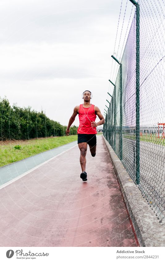 Man running along fence Jogging Track Running Town sportsman Healthy workout Action Speed in motion Nature Practice Athletic Wellness Black