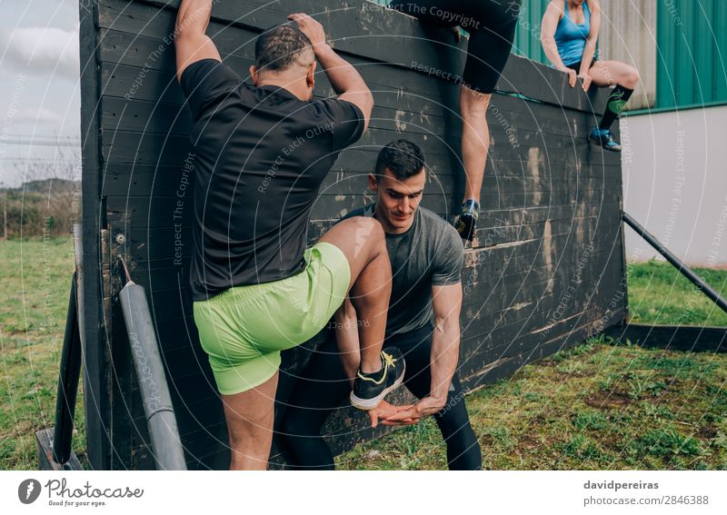 Participants in obstacle course climbing wall Sports Climbing Mountaineering Human being Woman Adults Man Hand Feet Group Authentic Strong Black Effort