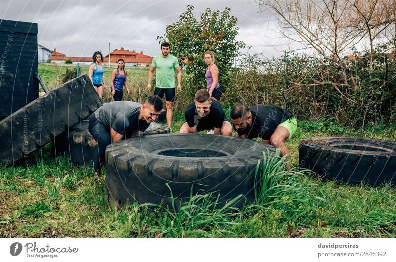 Participants in an obstacle course turning a wheel Sports Human being Woman Adults Man Group Observe Authentic Strong Black Power Effort Teamwork