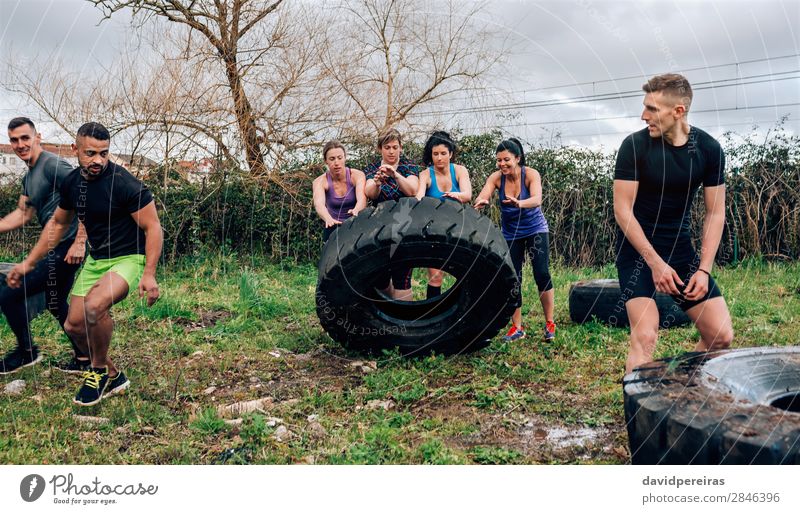 Group in obstacle course turning truck wheel Sports Human being Woman Adults Man Authentic Strong Black Power Effort Competition Teamwork obstacle course race