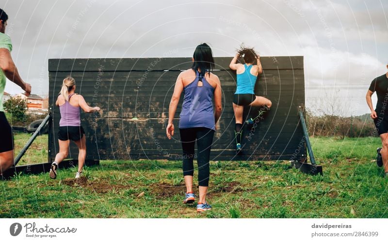 Participants in obstacle course climbing wall Lifestyle Sports Climbing Mountaineering Human being Woman Adults Man Group Jump Authentic Strong Effort