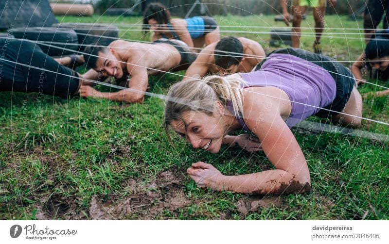 Participants in obstacle course crawling under electrified cables Joy Happy Sports Human being Woman Adults Man Group Authentic Dirty Effort Competition