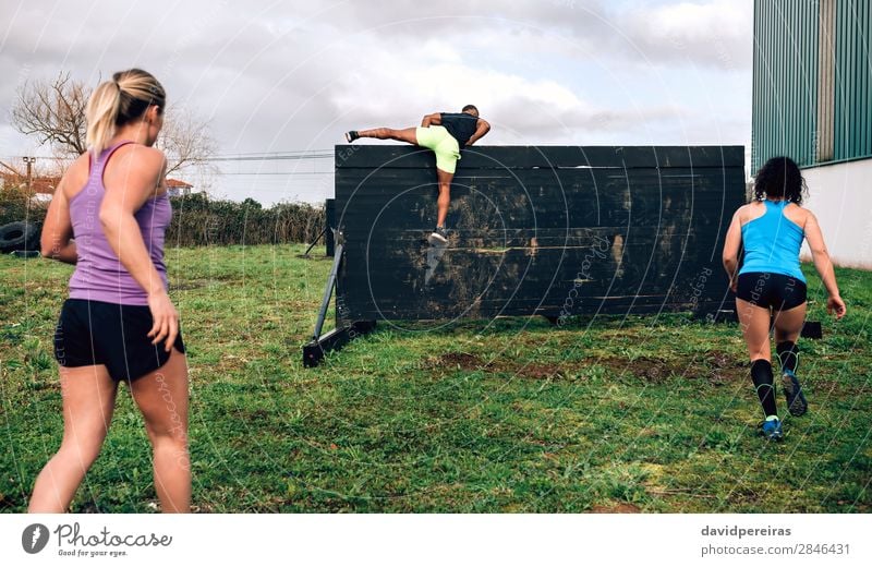 Participants in obstacle course climbing wall Lifestyle Sports Climbing Mountaineering Human being Woman Adults Man Group Jump Authentic Strong Black Effort