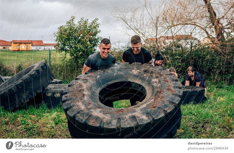 Participants in obstacle course turning truck wheel Sports Human being Woman Adults Man Group Authentic Strong Power Effort Competition Teamwork