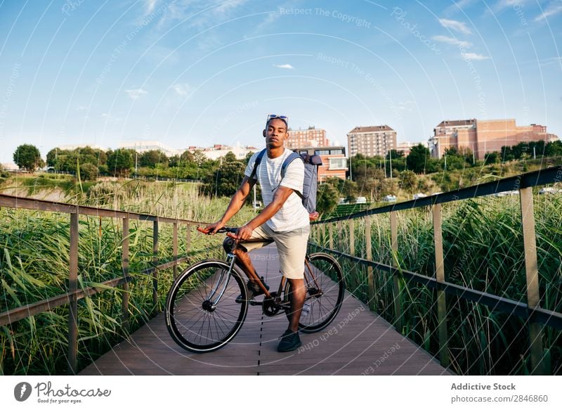 Young man posing with bike on pavement Man Bicycle Pavement Grass Bridge Handrail Street Lifestyle Transport Town Cycle City Action Alley Motorcycling handsome