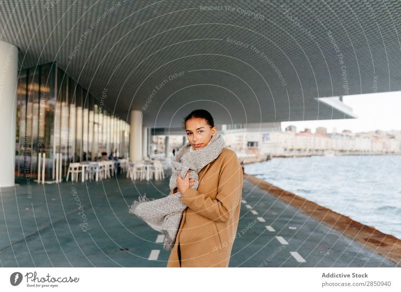 Young woman in coat walking near water Woman Water Walking Footpath Coast way Lanes & trails Easygoing Leisure and hobbies City Town Coat Scarf Warmth Style