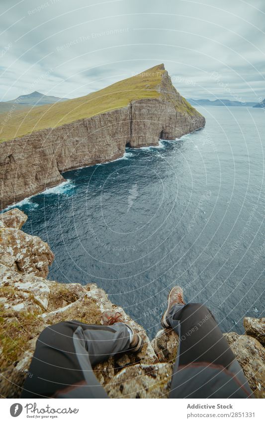 Anonymous man sitting on cliff Landscape Cliff Height Highlands Ocean Rock Dramatic scenery Freedom Mountain Panorama (Format) Vantage point Nature