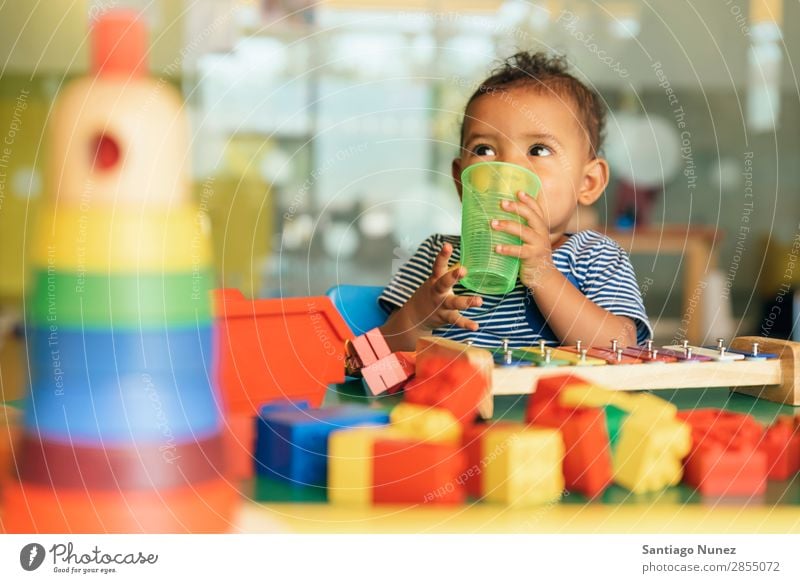 Happy baby drinking water and playing. Baby Playing childcare Kindergarten School Toys Toddler Girl Small Child blocks Considerate Story Cute Joy Preschool