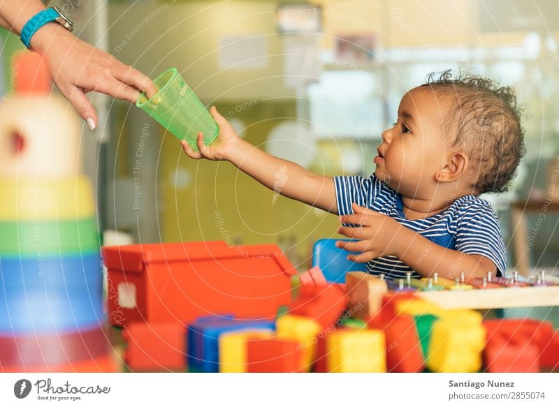 Happy baby drinking water and playing. Baby Playing childcare Kindergarten School Toys Toddler Girl Small Child blocks Considerate Story Cute Joy Preschool