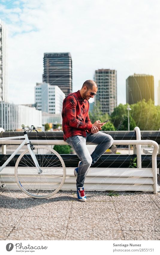 Young man with mobile phone and fixed gear bicycle. Mobile Man Bicycle fixie Telephone Hipster Lifestyle Stand Cycling City Building Solar cell Town Human being