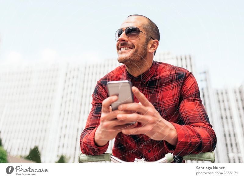 Young man using his mobile in the street. Mobile Man Portrait photograph Happy Bicycle fixie Smiling Telephone Hipster Lifestyle Stand City Solar cell Town