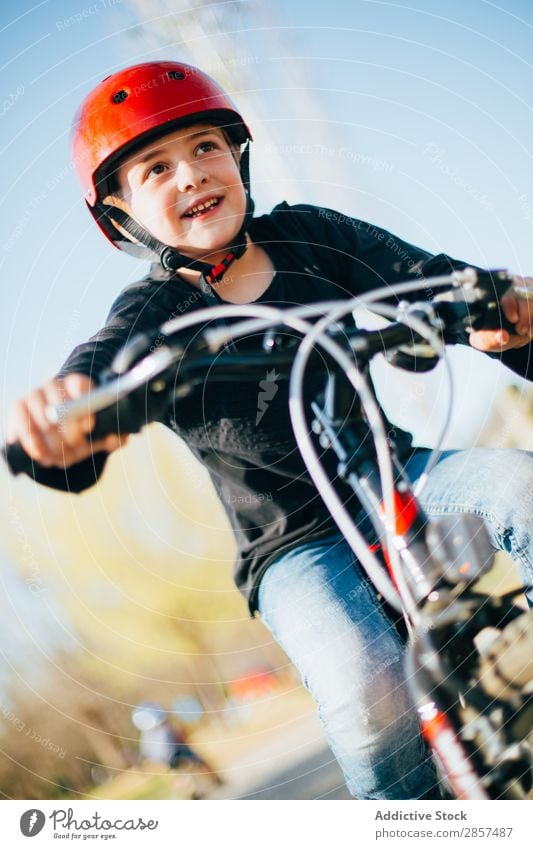 Boy resting after riding her bike Bicycle Boy (child) Caucasian Child Landscape Cute Joy Happy Helmet Lifestyle Exterior shot Park Sports Sunset Tree