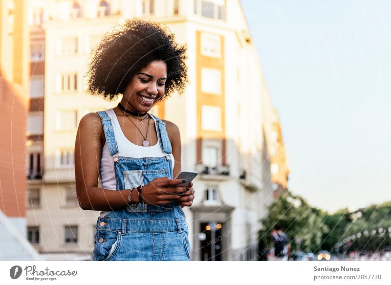 Beautiful woman using mobile in the Street. Woman Telephone Black African Mobile PDA texting Communication Afro Human being Portrait photograph City