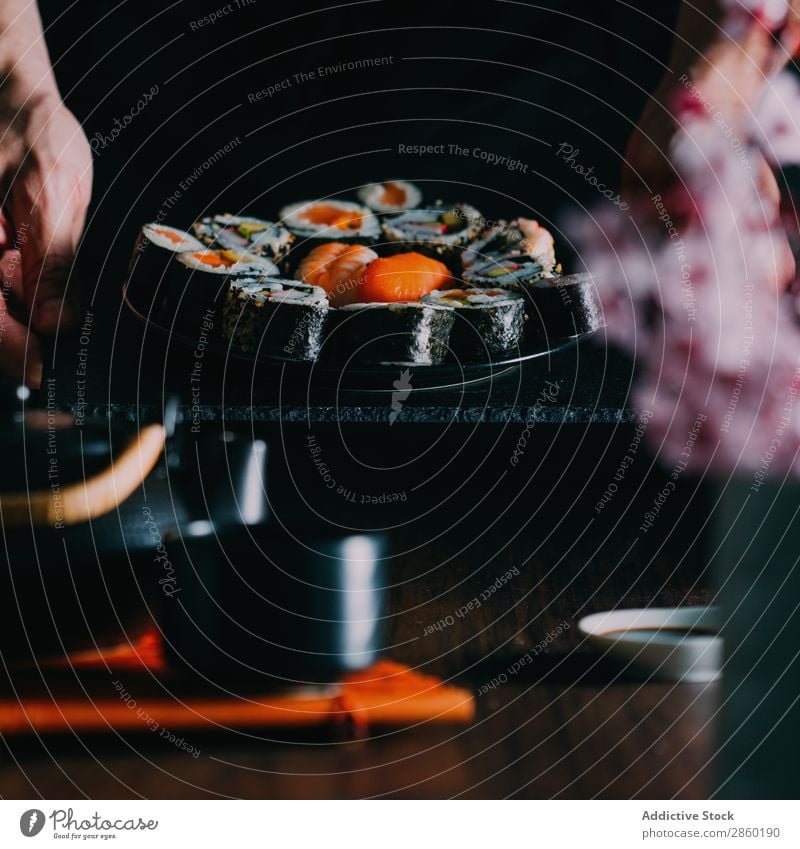 Man holding some sushi served on blackboard asian Avocado Chopstick Dish Fish Flower Food Ginger Hand Hold Japanese maki nigiri nori Raw Rice Salmon sashimi