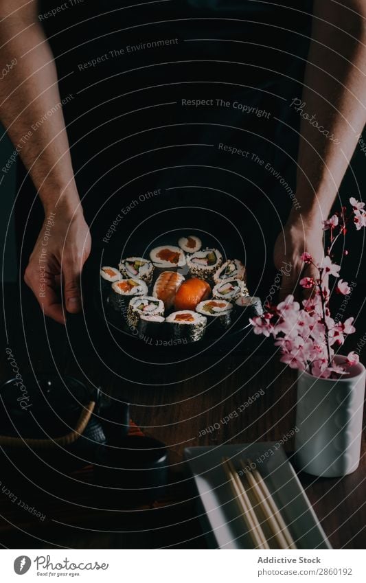 Man holding some sushi served on blackboard asian Avocado Chopstick Dish Fish Flower Food Ginger Hand Hold Japanese maki nigiri nori Raw Rice Salmon sashimi