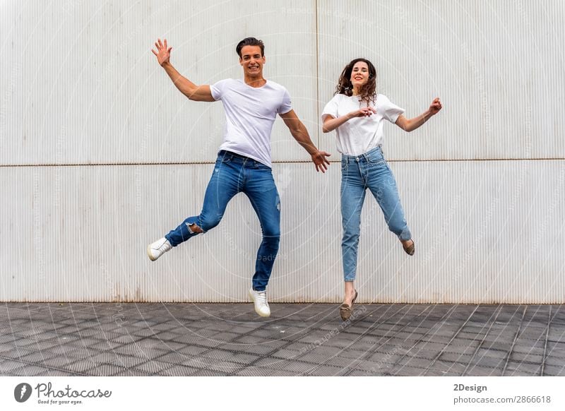 Side view Happy couple in love jumping against grey wall. Lifestyle Joy Leisure and hobbies House (Residential Structure) Human being Masculine Feminine