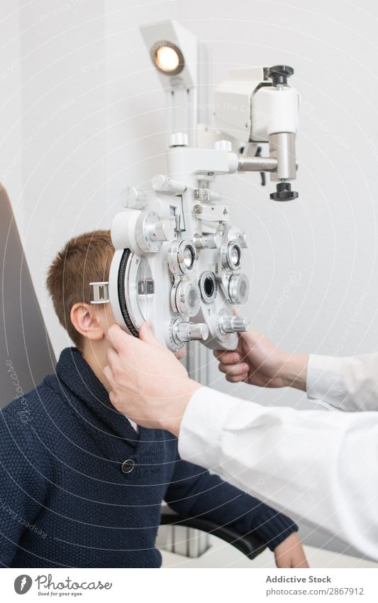 Optician testing a boy's eyes Boy (child) Child clinic device diagnose Display Doctor Examinations and Tests Eyes Person wearing glasses Healthy Hospital