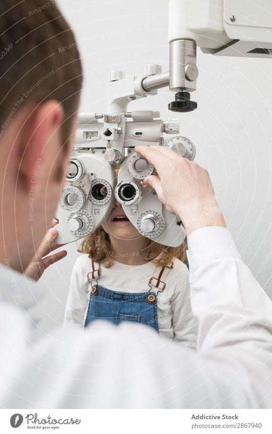 Optician testing a girl's eyes clinic device diagnose Display Doctor Examinations and Tests Eyes Person wearing glasses Healthy Hospital hygienics Child