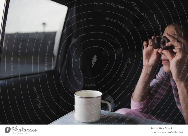 Woman with biscuits near eyes sitting in car with cup Car Eyes Sit Cup Looking Chocolate Cookie Mug Spoon Table Youth (Young adults) Snack Food Lady Tasty Trip