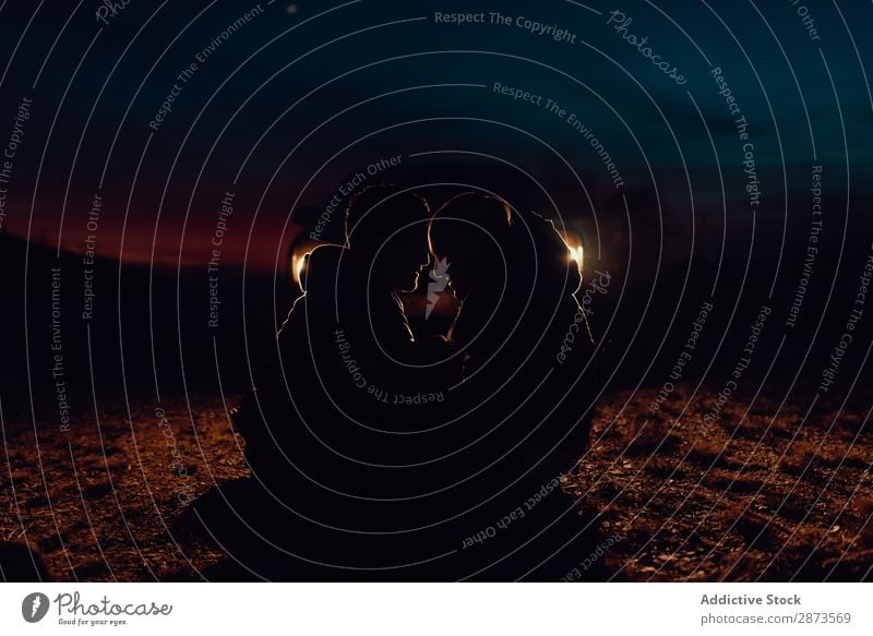 Men hugging and sitting on ground on field at night Homosexual Couple Field Ground Embrace Night Landscape Landing Love embracing headlights Sit Nature