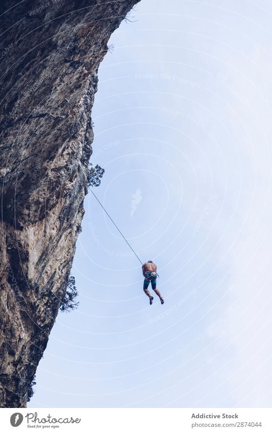 Anonymous climber handing on cliff Climber Cliff Hanging Rope Extreme Sky Blue Mountain Rock Sports challenge Action Success Power Height Adventure Risk belay