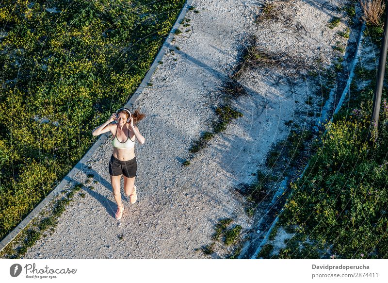 Young fit blonde woman running in the park Woman Running Practice Bird's-eye view Fitness work out Lifestyle Music Headphones Technology Movement Action Jogging