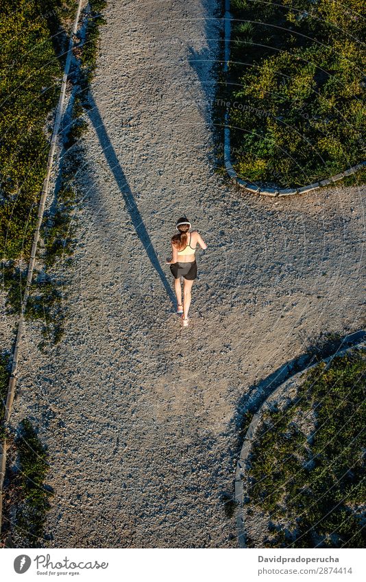 Young fit blonde woman running in the park Woman Running Practice Bird's-eye view Rear view Fitness work out Lifestyle Music Unrecognizable Anonymous Headphones