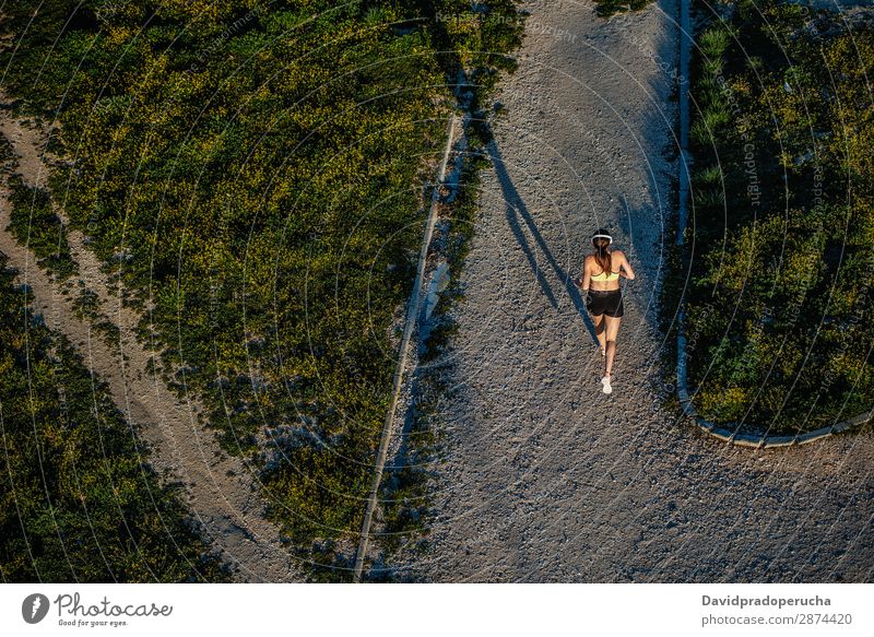 Young fit blonde woman running in the park Woman Running Practice Bird's-eye view Rear view Fitness work out Lifestyle Music Unrecognizable Anonymous Headphones