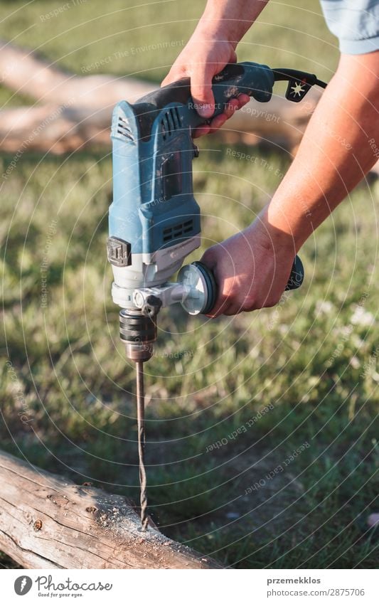 Man drilling hole in timber while working in garden House (Residential Structure) Garden Work and employment Craft (trade) Tool Human being Adults Grass