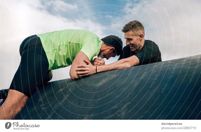 Male participant in obstacle course helped by teammate Lifestyle Joy Sports Climbing Mountaineering Human being Man Adults Hand To enjoy Authentic Strong Effort