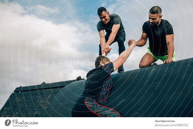 Female participant in obstacle course helped by teammates Lifestyle Joy Sports Climbing Mountaineering Human being Woman Adults Man Hand Group Fitness Authentic