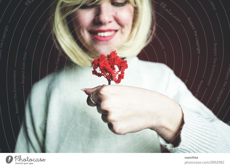 Young woman holding a little red tree Design Human being Woman Adults 1 Art Environment Nature Autumn Tree Smiling Growth Authentic Uniqueness Sustainability